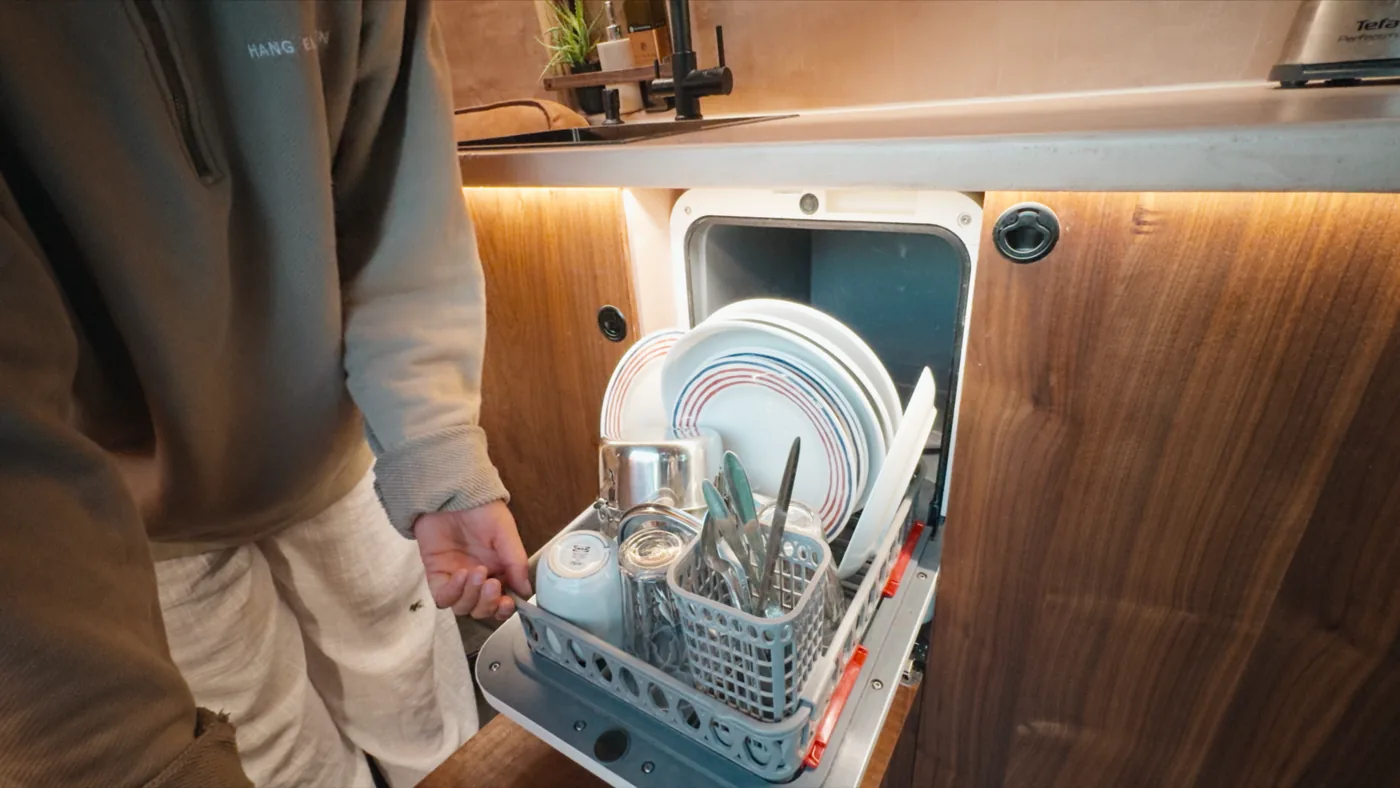 The dishwasher drawer open with a full set of plates and cutlery